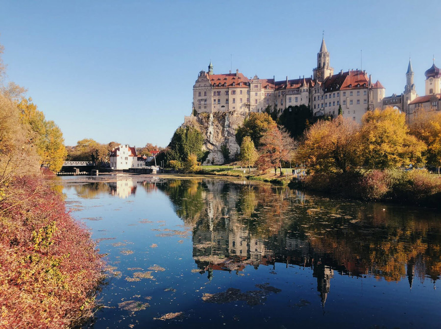 Hohenzollern Schloss Sigmaringen mit einem See und Bäumen.