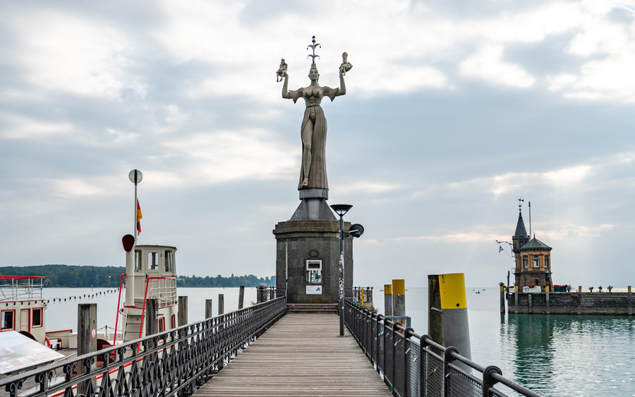 Am Ende eines Stegs der in den Bodensee führt steht eine Statue.