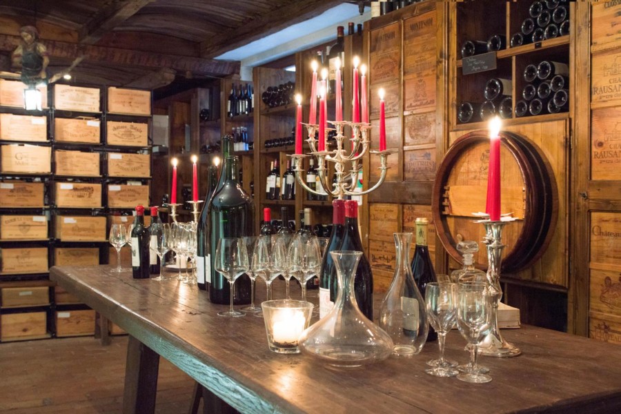 In einem Weinkeller stehen Weine und Weingläser für eine Weinprobe bei Kerzenschein bereit.