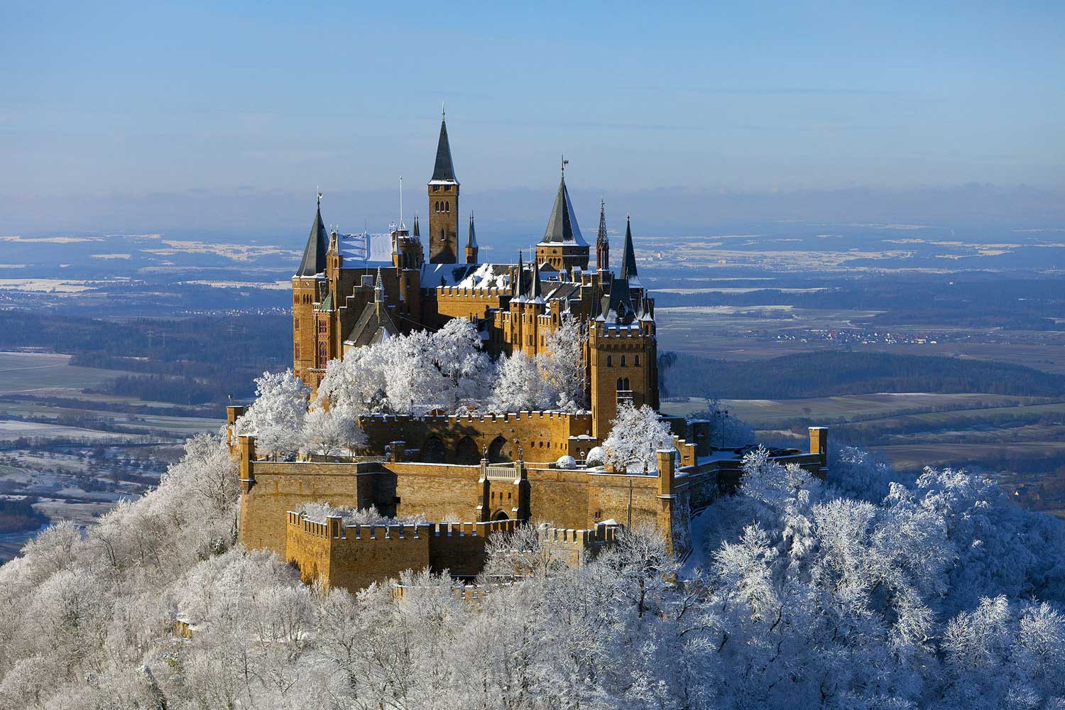 Burg Hohenzollern im Winter. Alle Bäume um die Burg herum sind weiß vom Schnee.