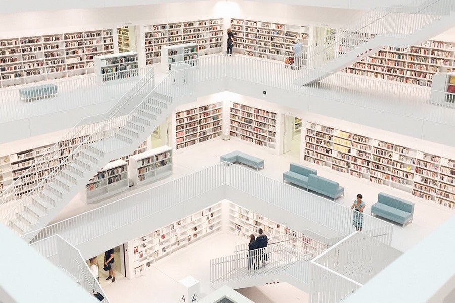 Stadtbibliothek Stuttgart von innen. Über mehrere moderne Etagen verteilt sind viele Bücherregale an den Wänden angebracht.