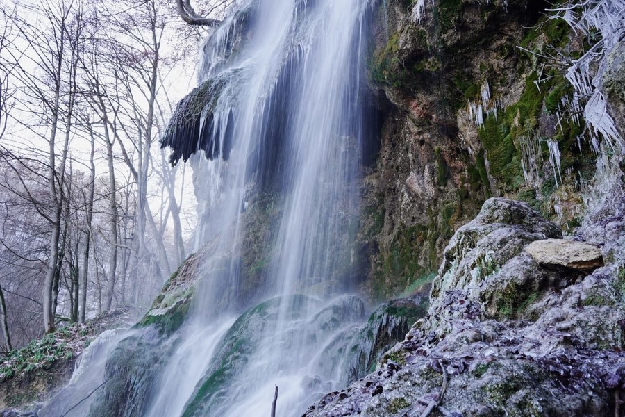 Das Wasser des Bad Uracher Wasserfalls schießt sturzartig am Hang hinunter.