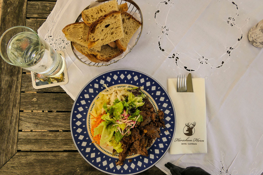 Auf einem gedeckten Tisch steht ein Korb mit Brot und ein Teller mit Rindergeschnetzeltem.