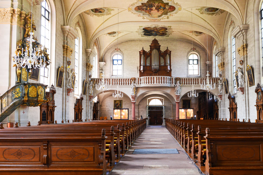 Kirchenschiff einer Kirche im Schwarzwald mit vielen Bänken und einem seitlichen Altar. 