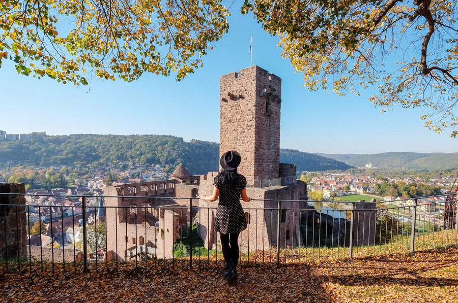 Eine Frau steht hinter einem Geländer und schaut auf die Burg Wertheim.