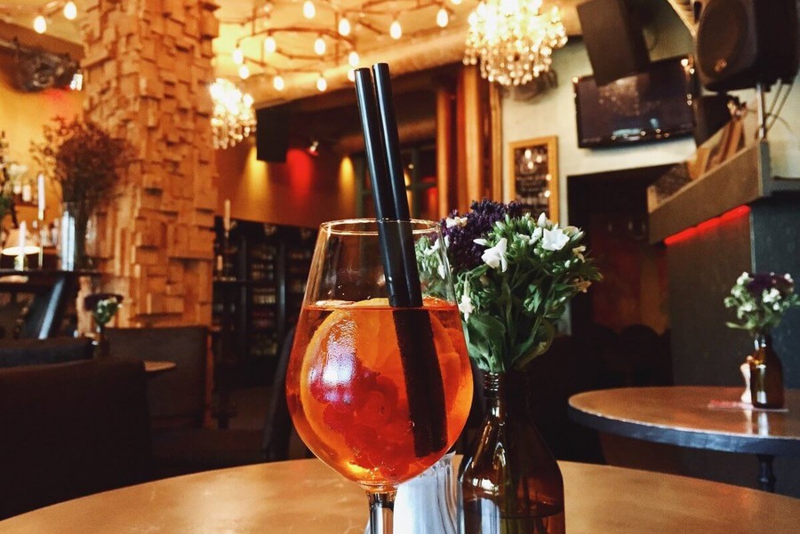 Auf einem Tisch in einer Bar steht ein Weinglas in das ein Cocktail gefüllt ist.