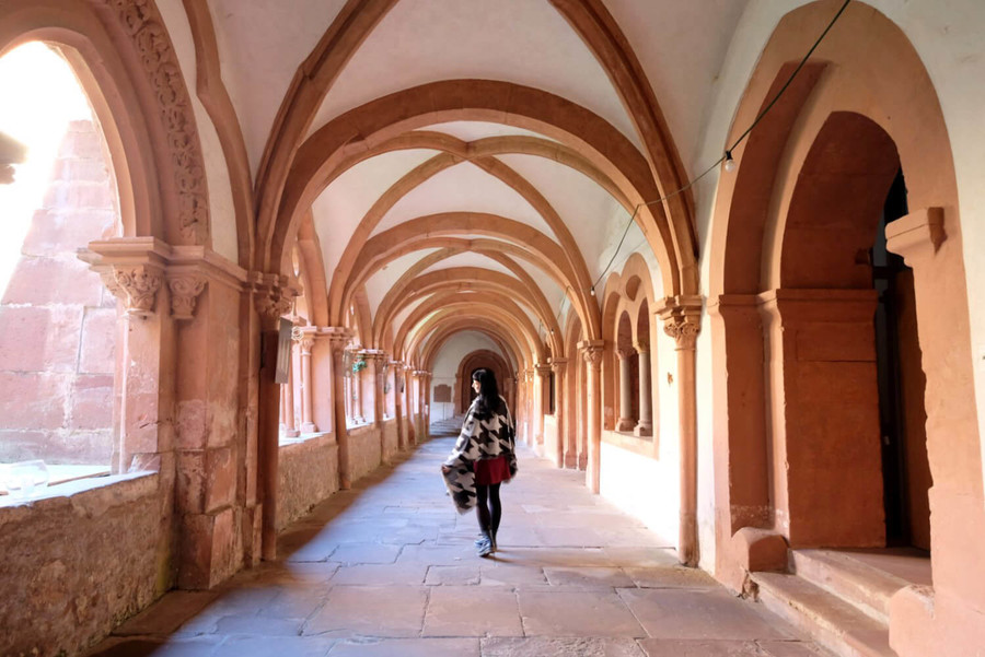 Im Säulengang des Klosters in Bronnbach steht eine Frau.