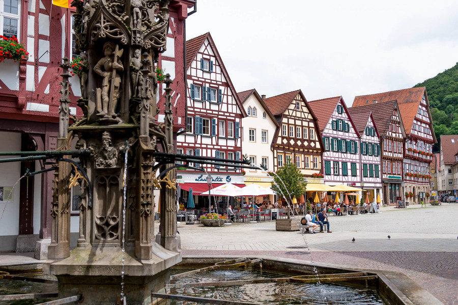 Marktplatz von Bad Urach mit vielen Fachwerkhäusern und einem Brunnen.