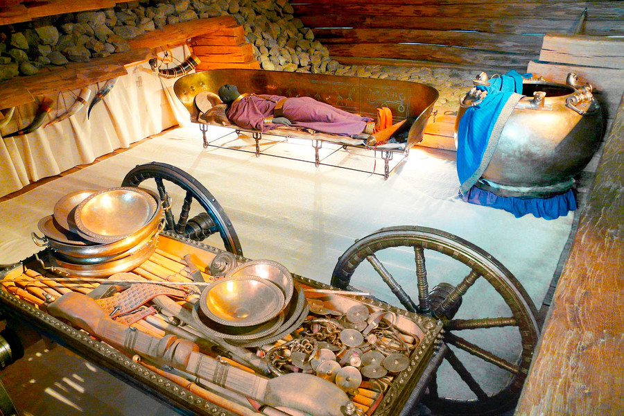 Einblick in ein rekonstruiertes keltisches Grab. Schmuckstücke und Geschirr liegen auf einem Handkarren in der Grabkammer.