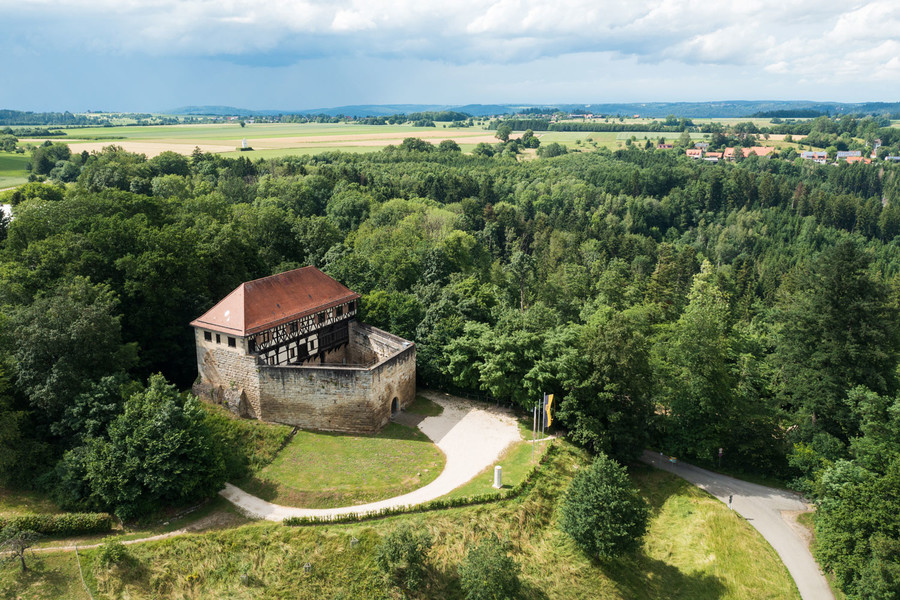 Luftaufnahme der kleinen Burg Wäscherschloss. Rundherum ist die Burg eingebettet in einem Wald.