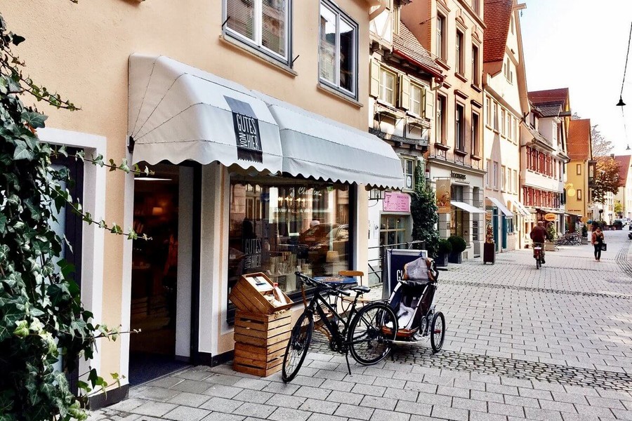 Ulmer Altstadt mit einem kleinen Geschäft vor dem ein Fahrrad mit einem Anhänger für Kinder steht.