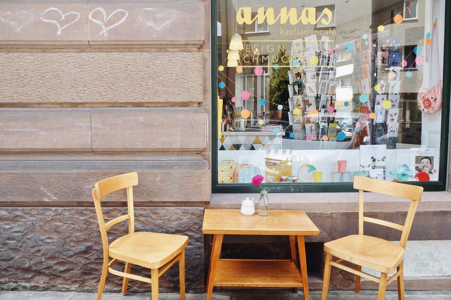 Annas Kaufladencafé im Stuttgarter Westen. Vor dem Schaufenster steht ein einfacher Holztisch mit zwei Stühlen.