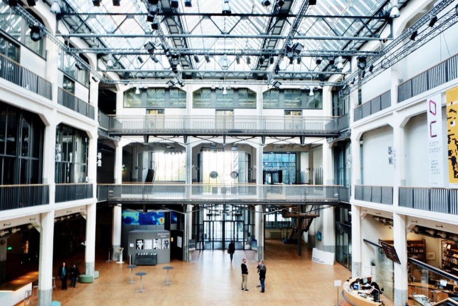 Innenaufnahme des ZKM in Karlsruhe. Das Gebäude besteht aus mehreren Stöcken und einem großen offenen Raum in der Mitte.