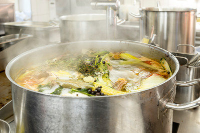 In einem großen Suppentopf kocht eine Suppe mit verschiedenen Gemüseeinlagen.