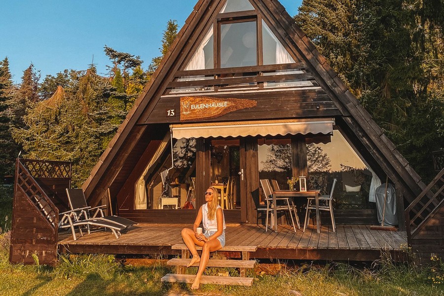 Eine Frau sitzt auf der Terrasse eines typischen Schwarzwälder Ferienhauses und genießt die Sonne.